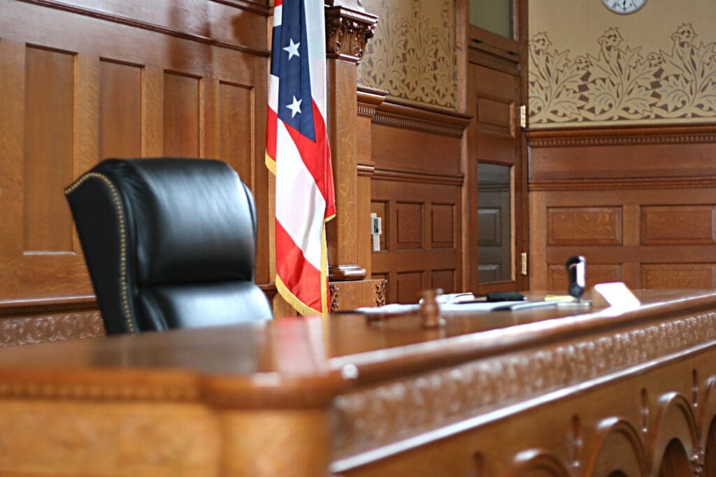 Toxic Tort Litigation, Fate and transport, Natural resource damage assessment, Exposure assessment, Forensic specialists, Construction claims--Empty courtroom with judge's bench and American flag for toxic tort litigation and expert testimony.
