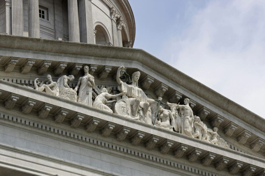 Courthouse pediment with Lady Justice holding scales symbolizing litigation and expert witness services.