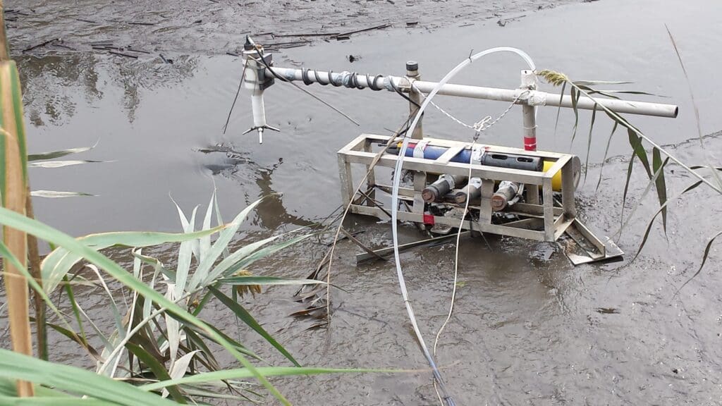 OPTICS water quality monitoring tool deployed in shallow water with sensors and equipment mounted on frame.